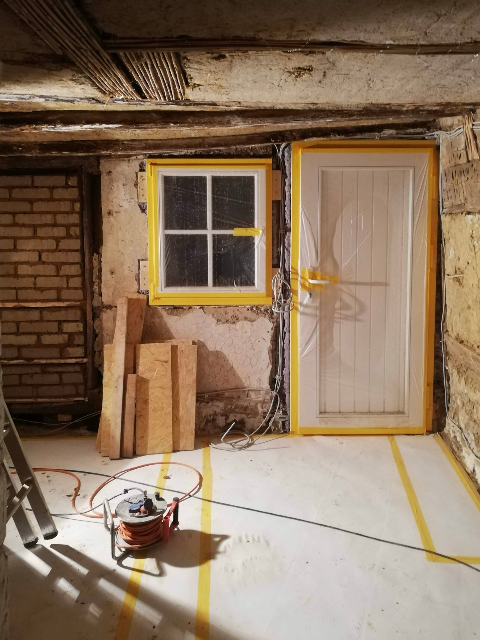 Innenwand im Umbau: neue Tür- und Fensteröffnungen mit gelben Schutzrahmen