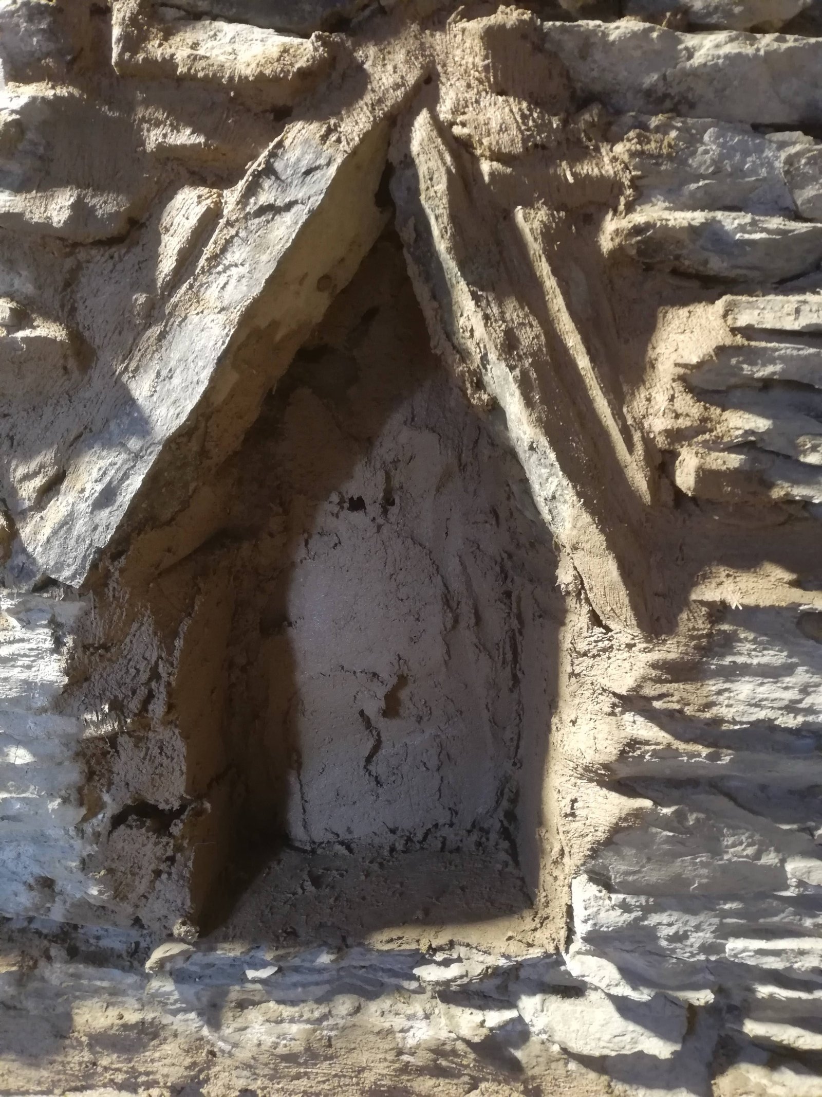 Historische gotische Bogennische in Bruchsteinmauer, Lehmverfugung sichtbar