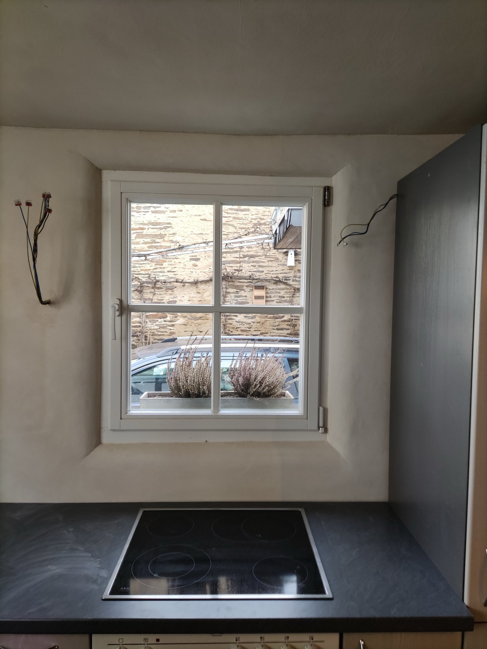 Küchenrückwand mit Kalkputz und Fenster, Glaskeramik-Kochfeld auf Holzarbeitsplatte