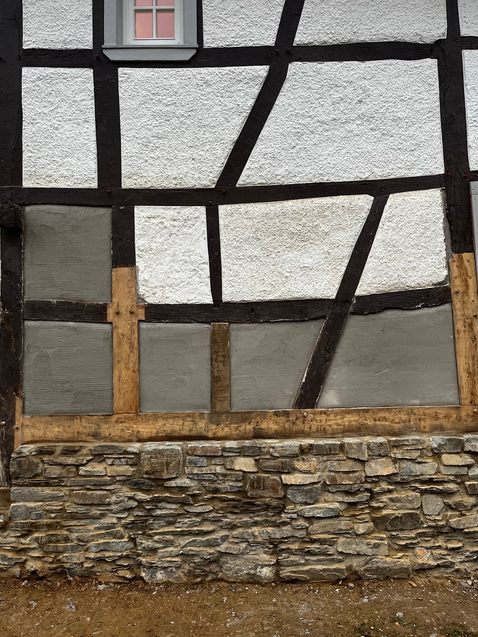 Außenansicht saniertes Fachwerkhaus Ahrtal: schwarze Balken, weiße Gefache, Blumenkasten