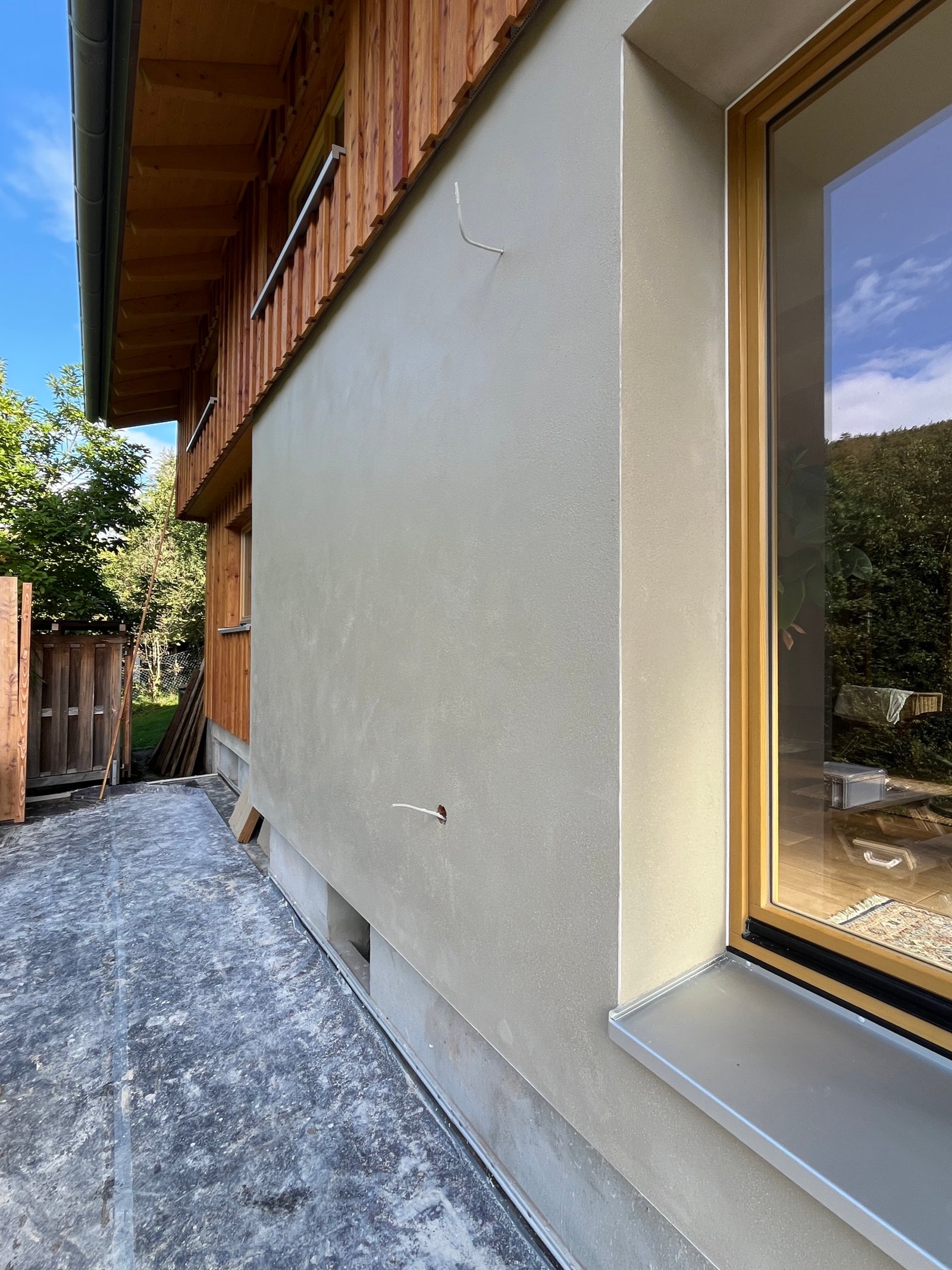 Kalkputzfassade fertig: heller Ton, Fenster mit Holzrahmen, Reflexion im Glas