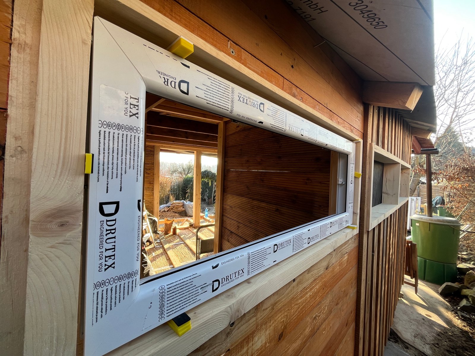 Gartenhaus-Innenraum nach Lehmputz: warme Erdtonwände mit Dachfenstern, fertig