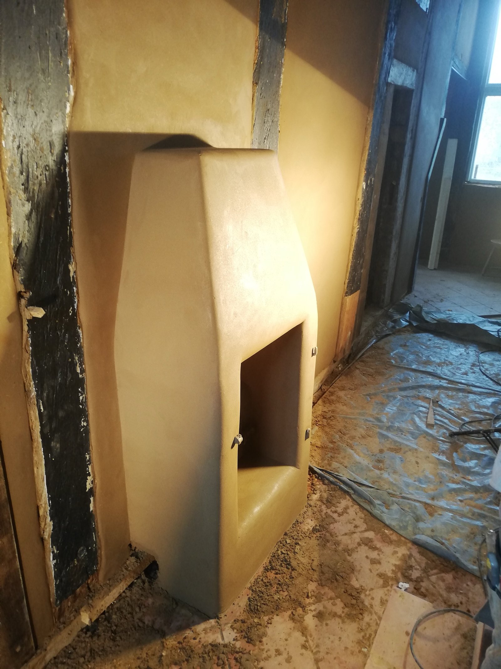 Lehmputzraum mit Terrakottafliesen: warme Erdtöne, Dachbalken, Baumaterialpuffer