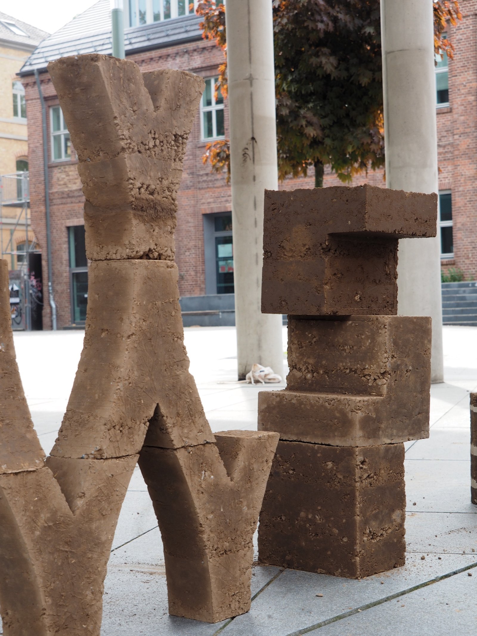 Lehmziegel-Skulpturen im Workshop: zwei geformte Lehmkörper auf Dachterrasse