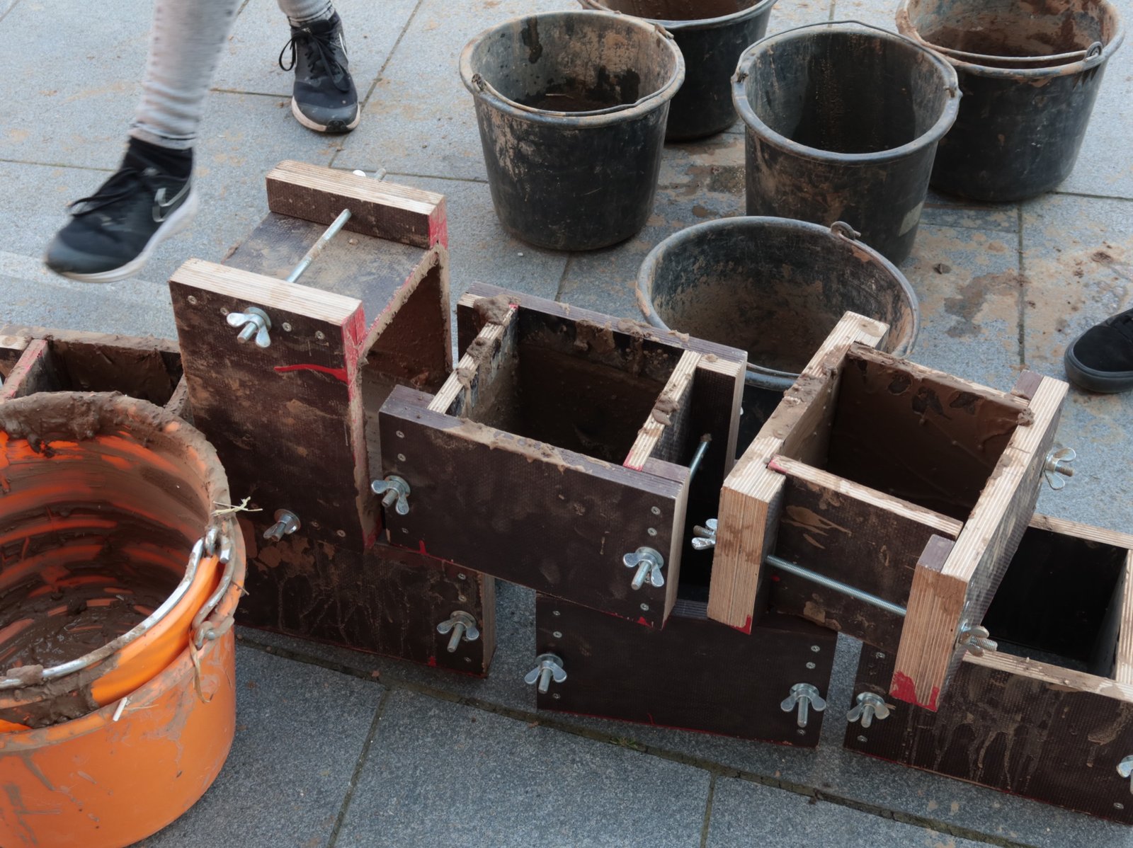 Stampflehmschalung: Holzschalungsrahmen mit Spannern auf Pflasterstein