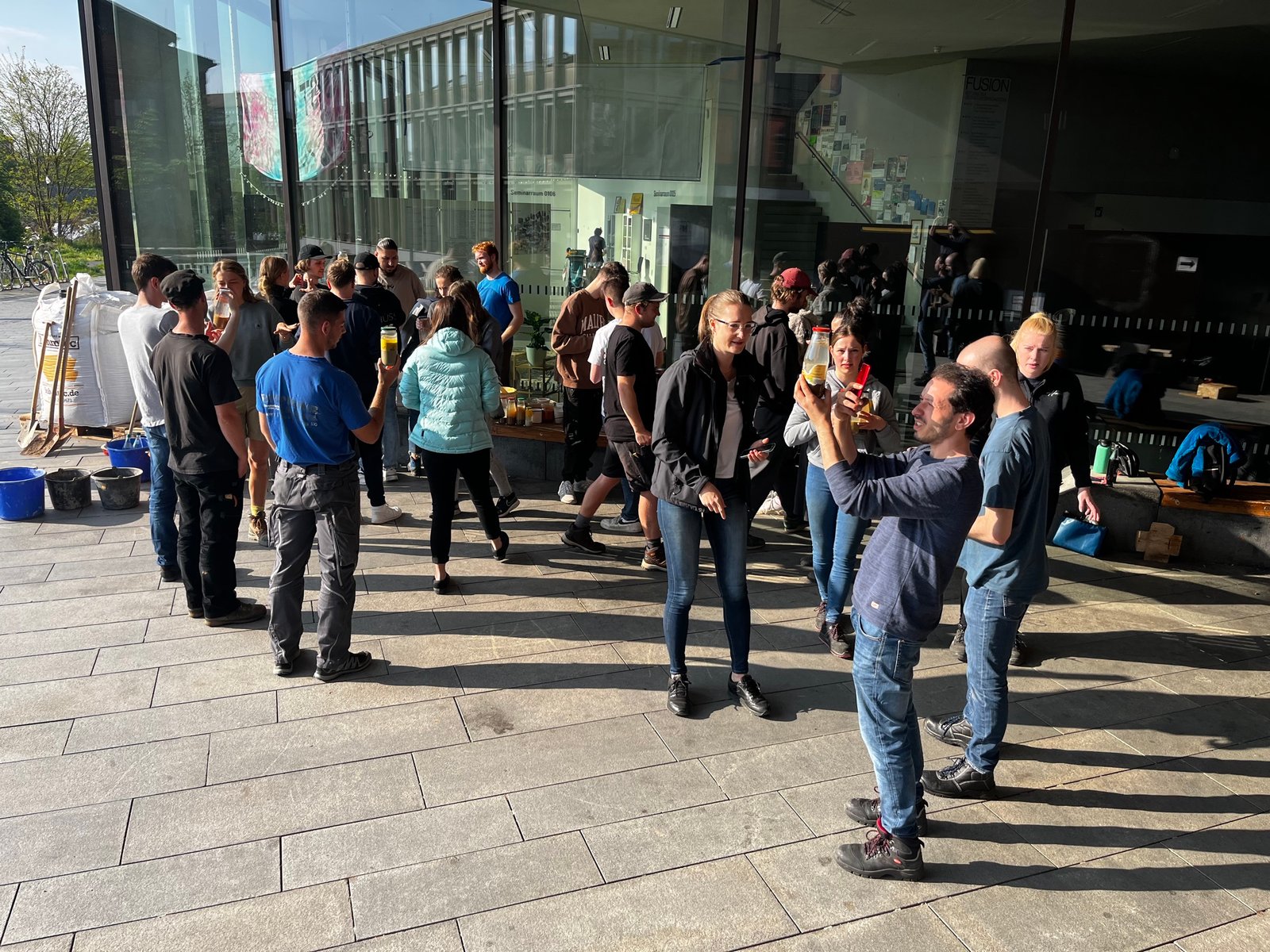 Workshop-Abschlussveranstaltung: Studierende bei Apéro vor Glasfassade