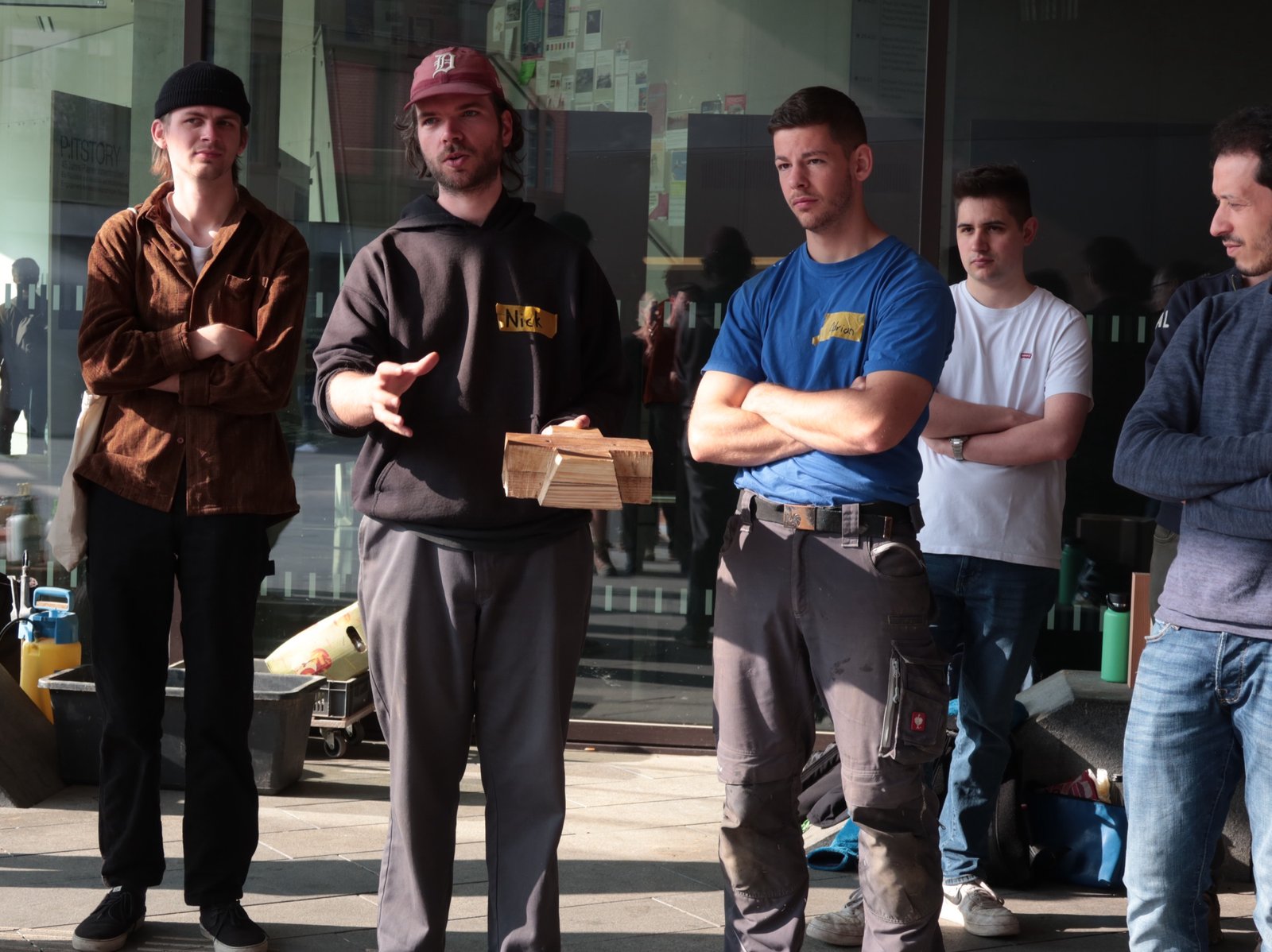 Lehm-Workshop: Lehrperson erklärt Stampflehm-Technik, Studierendengruppe zuhört