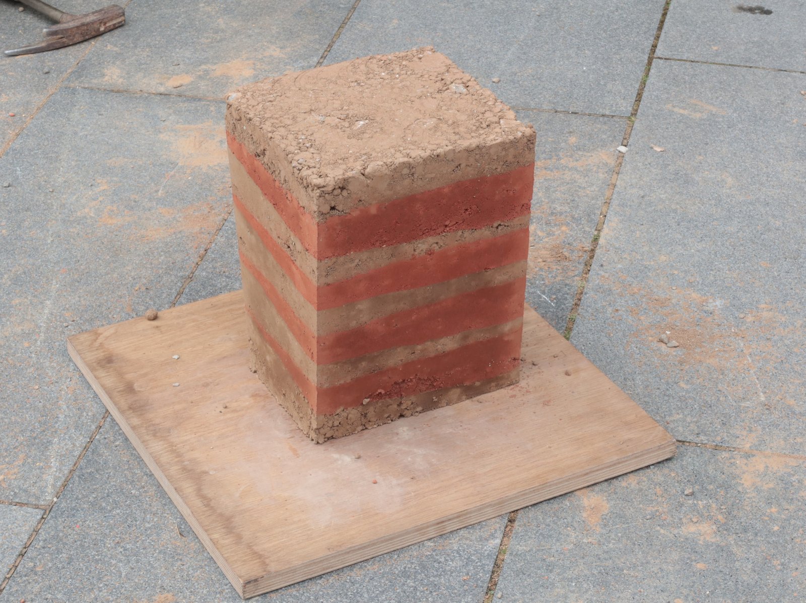 Stampflehm-Workshop: Studierender befüllt Schalung mit Lehmmasse von oben