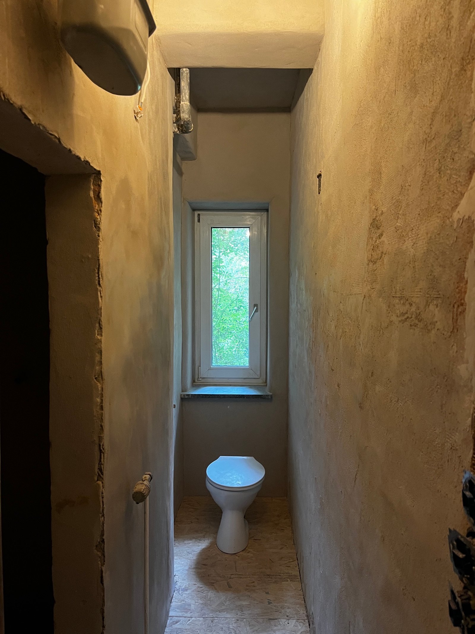 Saniertes Badezimmer im Rohbau: Lehmputzwände, freiliegende Sanitärinstallation