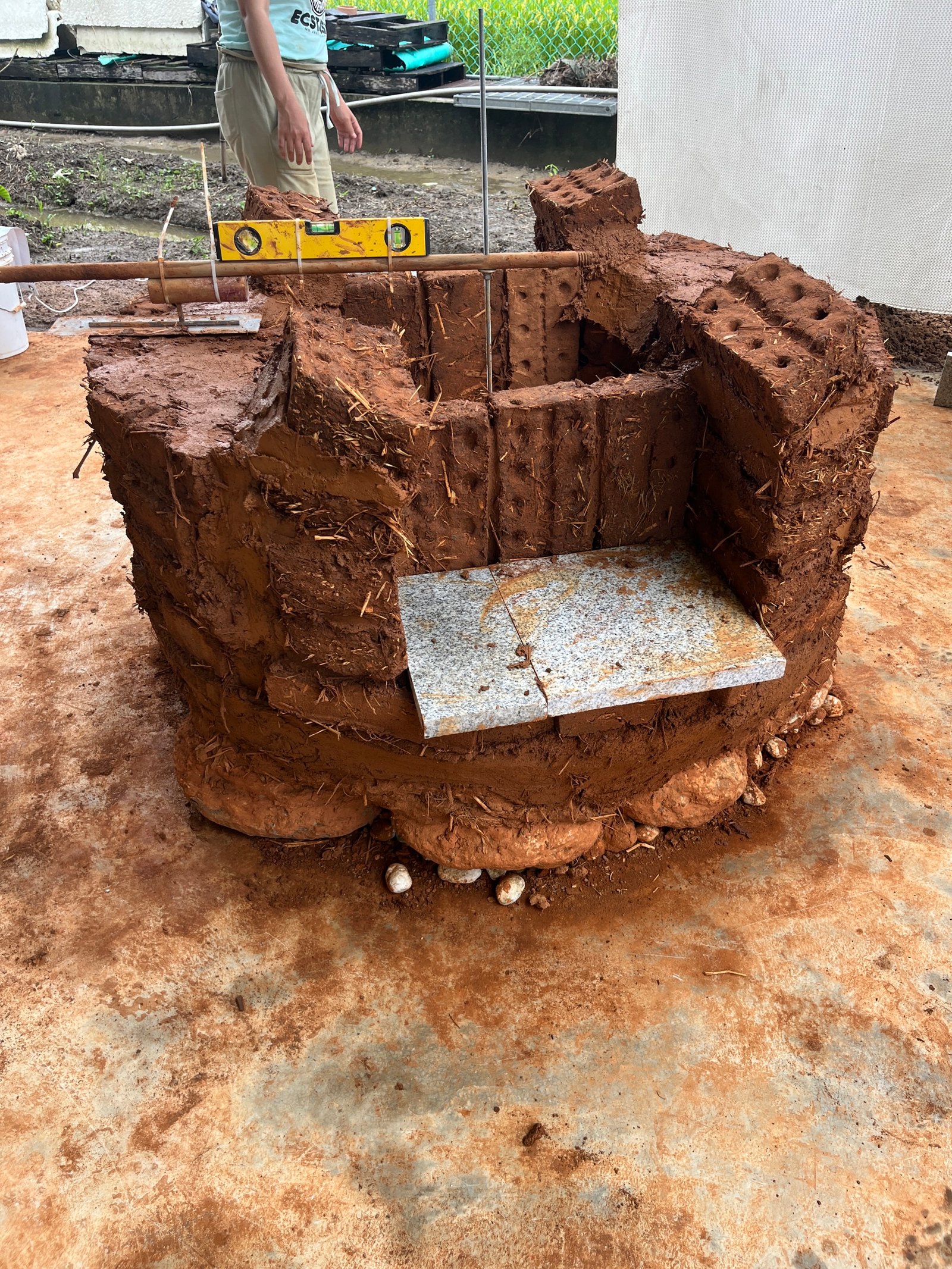 Lehmbackstein-Ofenbau im Rohbau: runde Form mit Ziegeln und Lehmverputz